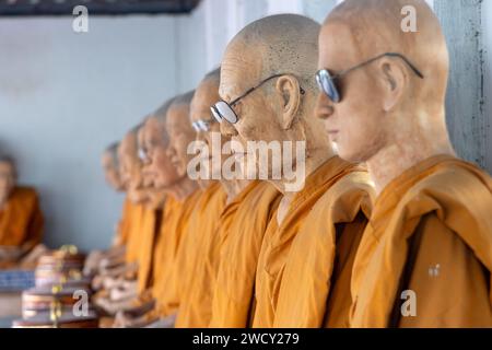 SAMUT SAKHON, THAILANDIA, DEC 03 2023, Una fila di statue di cera di monaci buddisti seduti in un tempio buddista Foto Stock