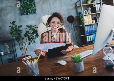 Ritratto di un'elegante ed allegra poltrona economista, porta appunti documenti di revisione annuale all'interno del business center Foto Stock
