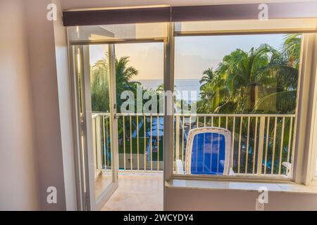 Una splendida vista dalla camera attraverso la porta aperta del balcone dell'hotel, che si affaccia sulle palme da cocco sullo sfondo dell'Oceano Atlantico. Foto Stock