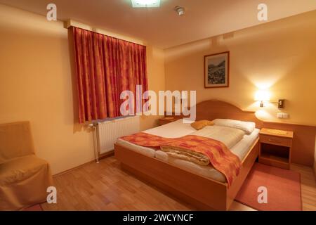 Camera d'albergo alpina pulita di colore arancione con letto e tavolo a Schottwien Austria 01 13 2024 Foto Stock