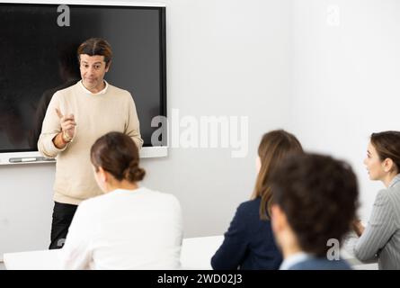 Insegnante di sesso maschile con esperienza che dà lezioni a un gruppo di studenti Foto Stock