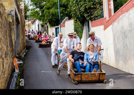 I turisti sono spinti in discesa da caroseiros, carros de cesto, giro sul Monte toboga, carrelli di vimini montati su pattini, Funchal, Isola di Madeira, Portogallo Foto Stock