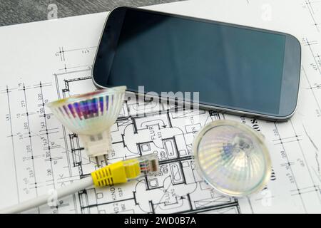 Lampade a riflettore, cavo di rete e smartphone sul disegno di costruzione, immagine simbolica per Smart Home Foto Stock