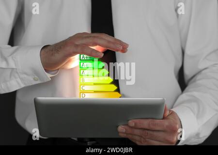 Valutazione dell'efficienza energetica fornita dai tablet. Uomo che usa il dispositivo, primo piano Foto Stock