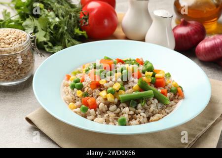 Saporito porridge di orzo perlato con verdure su un tavolo leggermente strutturato, primo piano Foto Stock