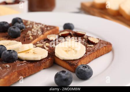 Tosta con gustosi burro di noci, fette di banana, mirtilli e nocciole su piatto, primo piano Foto Stock