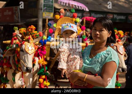 Bagan, Myanmar - 25 dicembre 2019: Una donna porta il suo bambino tra le braccia durante lo Shinbyu, una cerimonia di noviziazione, nella tradizione di Theravada B. Foto Stock