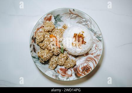 Nasi Ayam Gandum o pollo alla farina di grano con riso su un piatto sul tavolo bianco Foto Stock