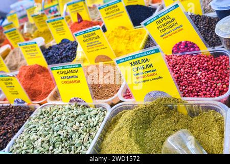 Vista dettagliata presso un fornitore che vende frutta secca, noci e molte spezie, erbe e condimenti. Presso il principale mercato alimentare locale dell'era sovietica, il Bazar verde. In Foto Stock