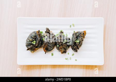 Black Fried Gyoza su un piatto su un tavolo di legno. Cibo di strada tradizionale giapponese. Orizzontale, vista dall'alto o ripresa dall'alto. Foto Stock