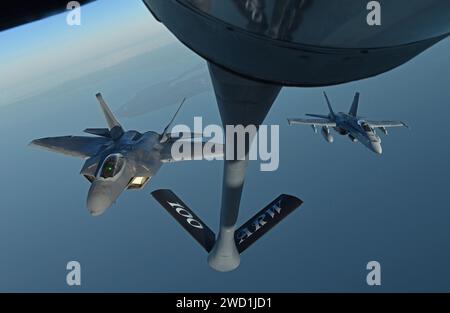 Un F-22 Raptor dell'aeronautica statunitense e un F/A-18 Hornet dell'aeronautica finlandese volano dietro uno Stratotanker KC-135. Foto Stock
