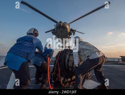 I marinai a bordo della USS Mahan si preparano ad attaccare un carico ad un elicottero durante un rifornimento verticale. Foto Stock