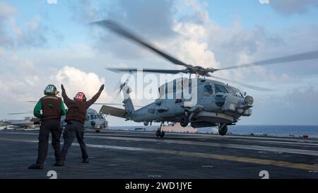 Airman directs a MH-60R Sea Hawk as it prepares to land aboard the aircraft carrier USS Carl Vinson. Stock Photo