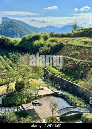 Un pittoresco ponte si estende su un tranquillo torrente tra maestose montagne Foto Stock