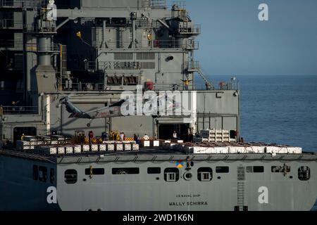 Un elicottero MH-60S Sea Hawk preleva ordigni dal ponte di volo dell'USNS Wally Schirra. Foto Stock