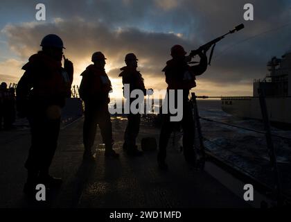 Gunner's Mate lancia una linea di tiro a bordo della USS Pinckney durante un rifornimento in mare. Foto Stock