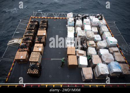 Marinai e marines ispezionano i pallet di rifornimento sull'ascensore della USS Bonhomme Richard. Foto Stock