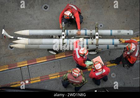 I marinai gestiscono ordigni a bordo della portaerei USS Nimitz. Foto Stock