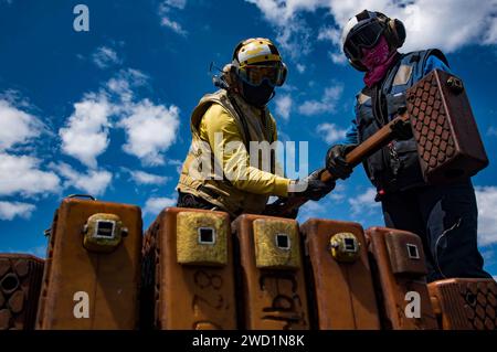 Aviation Boatswains Mates organizza cunei per ruote sulle passerelle della USS Dwight D. Eisenhower. Foto Stock