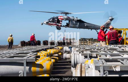 I marinai attaccano un pallet di ordigni a un MH-60S Sea Hawk a bordo dell'isola USS Makin. Foto Stock