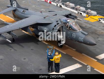 Airman utilizza una scheda tote per comunicare con il pilota di un AV-8B Harrier a bordo della USS Wasp. Foto Stock