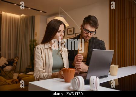 Giovani coppie di famiglie che utilizzano un computer portatile scelgono i prodotti da ordinare online a casa Foto Stock