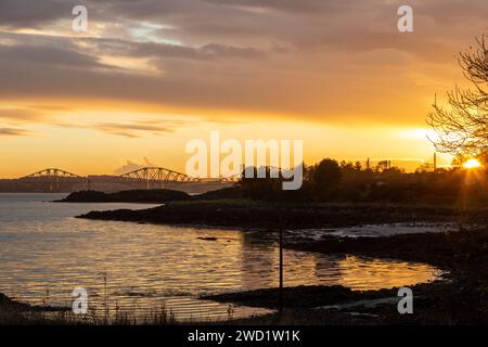 Un bellissimo tramonto nel Firth of Forth che guarda verso Downing Point nella Dalgety Bay e il Forth Bridge. Foto Stock