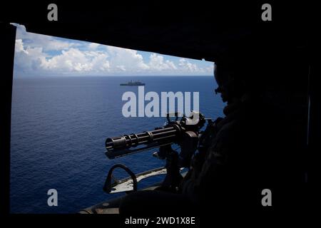 Un Marine americano guarda fuori dalla porta di un elicottero UH-1Y Huey alla USS New Orleans. Foto Stock