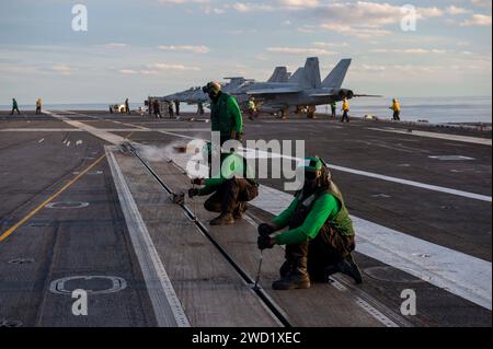 I marinai eseguono la manutenzione sul ponte di volo a bordo della USS Dwight D. Eisenhower. Foto Stock