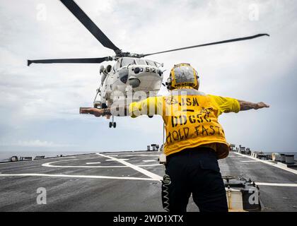 Il Boatswain's Mate segnala a un elicottero SH-60 della Japan Maritime Self Defense Force di atterrare sul ponte di volo. Foto Stock