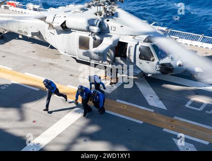 I marinai sgomberano un MH-60S Sea Hawk a bordo della nave d'assalto anfibio USS Iwo Jima. Foto Stock