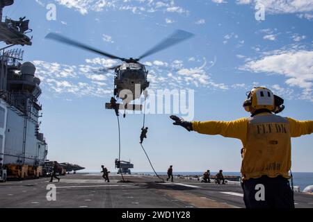 La fune veloce degli U.S. Marines da un elicottero US Navy MH-60S Sea Hawk a bordo dell'isola USS Makin. Foto Stock