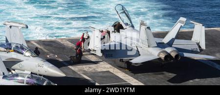 I marinai eseguono la manutenzione su un F/A-18F Super Hornet sul ponte di volo dello USS Nimitz. Foto Stock