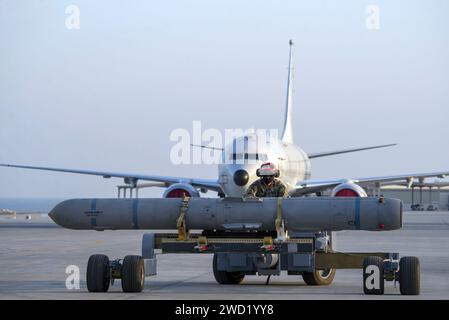 Aviation Ordnanceman si prepara a caricare un missile arpione AGM-84D su un P-8A Poseidon. Foto Stock