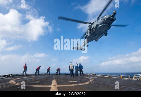 I marinai partecipano a un esercizio di rifornimento in elicottero con un MH-60S Sea Hawk a bordo della USS Sterett. Foto Stock