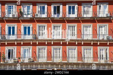 Vista frontale di una facciata arancione con porte jalousies bianche. Balconi con persiane bianche su un esterno arancione. Architettura latina o spagnola Foto Stock