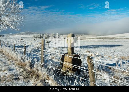 Altopiano di Aubrac in inverno. Croce di pietra sul lato di un sentiero. Lozere. Occitanie. Francia Foto Stock