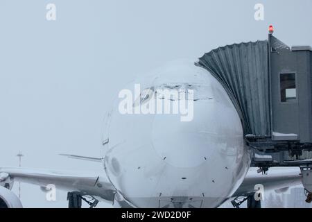 Aeroporto chiuso durante le forti nevicate. Aereo coperto di neve durante la gelida giornata invernale. Condizioni meteorologiche estreme durante il trasporto con spazio fotocopie. Foto Stock