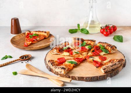 Tavola di legno e piatto con fette di gustosa pizza Margarita su sfondo bianco Foto Stock