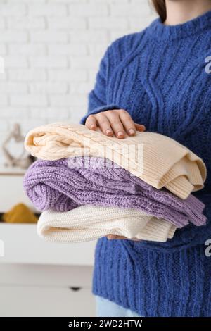 Donna con diversi pullover eleganti in camera Foto Stock