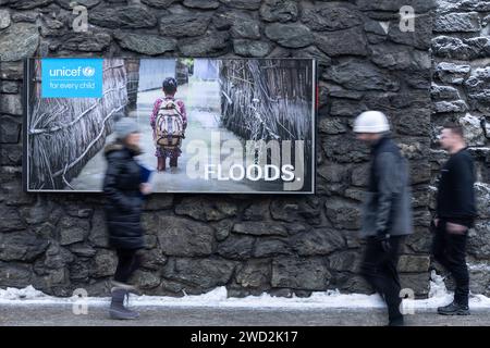 Davos, Svizzera. 18 gennaio 2024. La gente cammina davanti a un poster dell'unicef con l'iscrizione "alluvioni". L'incontro annuale del World Economic Forum è considerato uno dei luoghi di incontro più importanti per i politici, i top manager e gli scienziati. I dibattiti e le riunioni riservate si concentrano sulle soluzioni alle sfide globali. Credito: Hannes P. Albert/dpa/Alamy Live News Foto Stock