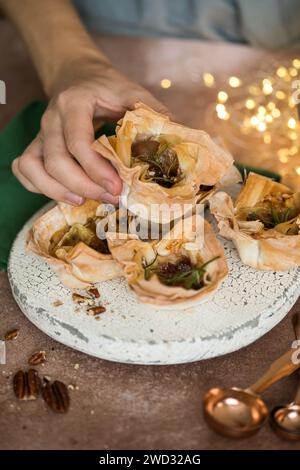 Tazze di pasta sfoglia phyllo con brie, marmellata, noci cosparse di zucchero in polvere . Delizioso dessert a base di pasta filo Foto Stock