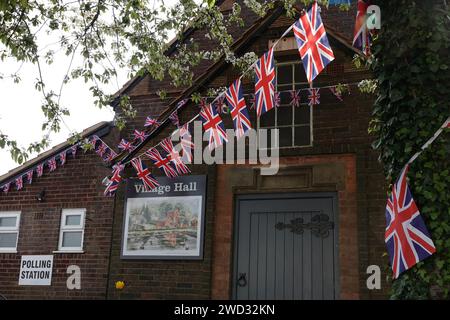 Un municipio del villaggio nel Regno Unito viene utilizzato come sede elettorale, con Union Jack o Union Flag Bunting esposto all'esterno Foto Stock