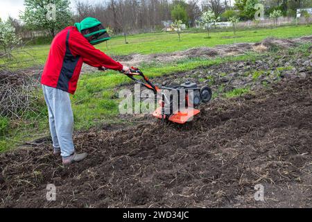 un coltivatore moderno, nelle mani di un coltivatore diligente, garantisce condizioni ottimali del terreno per una crescita efficace delle colture. Foto Stock