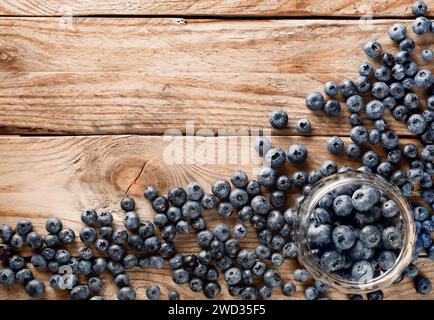 Pentola di vetro con fragole con bacche sparse nelle vicinanze su un vecchio tavolo rustico in legno. Vista dall'alto. Foto Stock