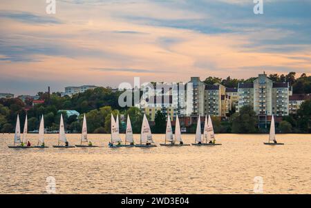 Barche a vela, barche a vela gommone, addestramento sul lago, al tramonto, in estate, a Stoccolma, Svezia, sul lago Mälaren. Parzialmente nuvoloso, arancione e rosa. Foto Stock