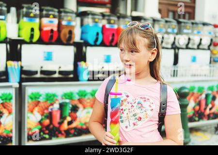 Carino bambina bere colorato slushie ghiacciato bere il caldo giorno d'estate Foto Stock