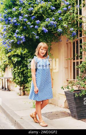 Una graziosa bambina turistica per le strade della Provenza, che indossa un abito Vichy blu e uno zaino. Concetto di viaggio con bambini. Immagine scattata ad Arles, p. Foto Stock