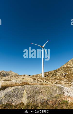 Turbina eolica su rocce contro il cielo azzurro sul passo del San Gottardo, Canton Ticino, Svizzera Foto Stock