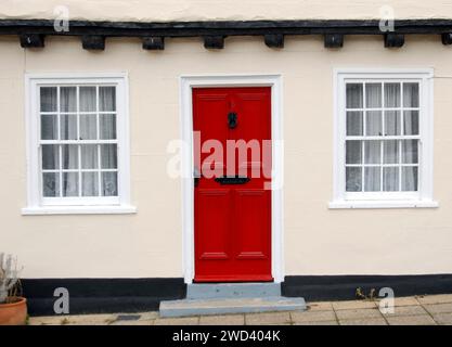 Parte di un antico edificio con una porta rossa brillante tra due finestre, Beccles, Suffolk, Inghilterra Foto Stock